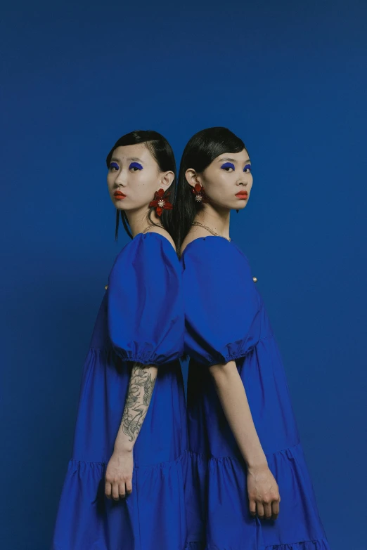 two women are standing in front of a blue background