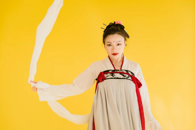 the young woman in a white dress with long white gloves holds a white scarf around her neck