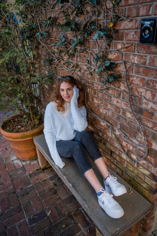 a woman sitting on a bench near a potted plant