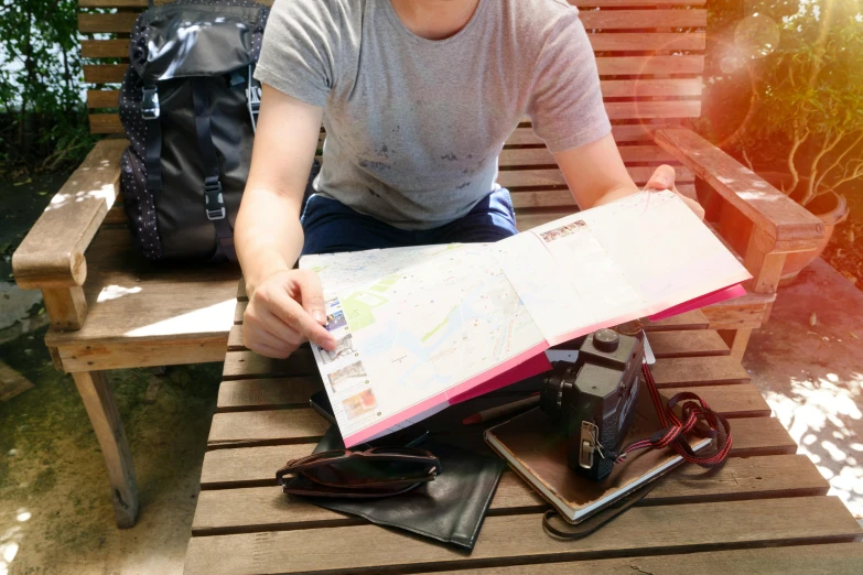 a man sitting on top of a bench holding a map