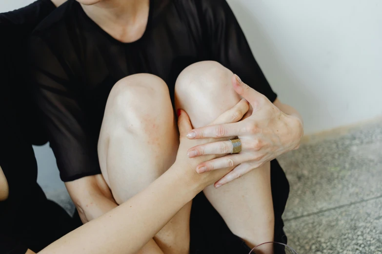 a woman holding her leg while wearing jewelry and a ring