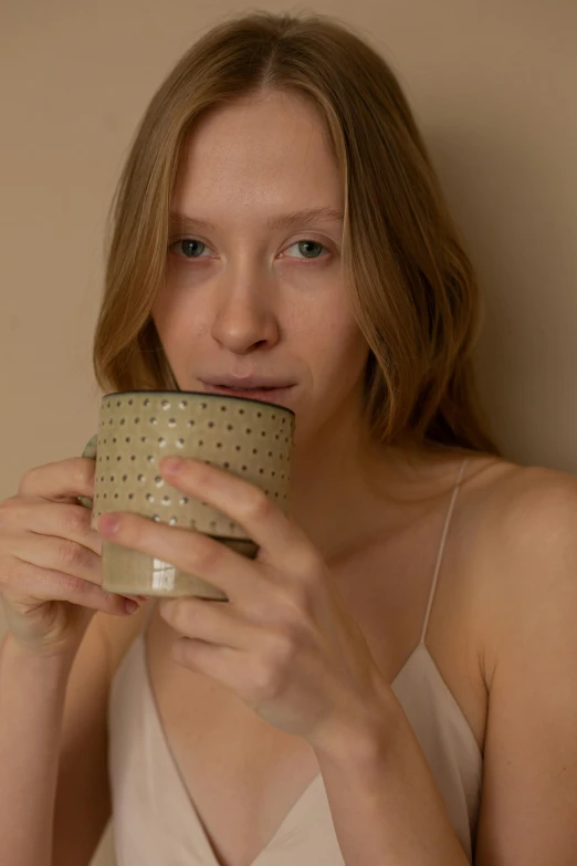 there is a young woman sitting with a cup in her hand