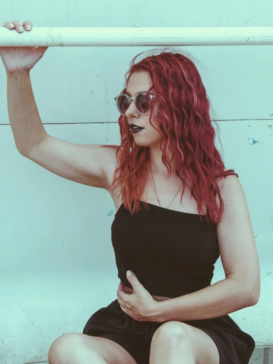 a girl in black dress sitting on the ground and wearing sunglasses