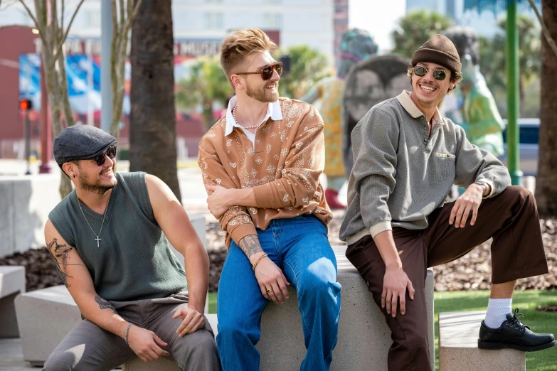 three guys sitting on a concrete bench, one smiling and the other not smiling