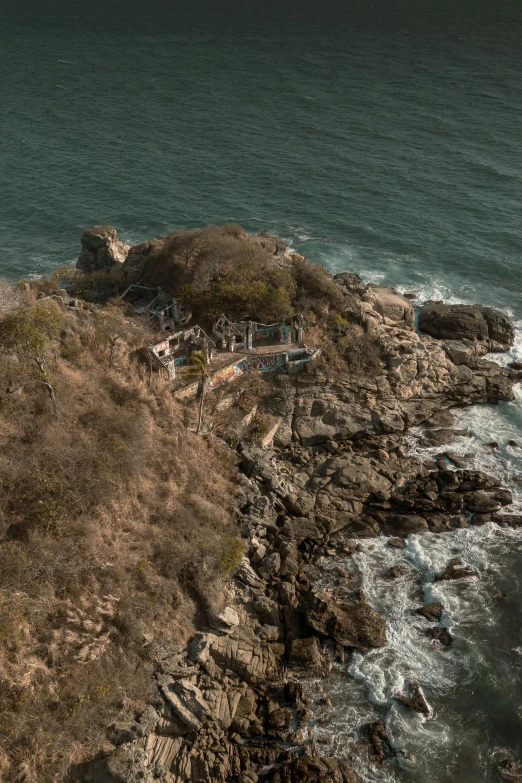 two large rocks next to a cliff next to the ocean