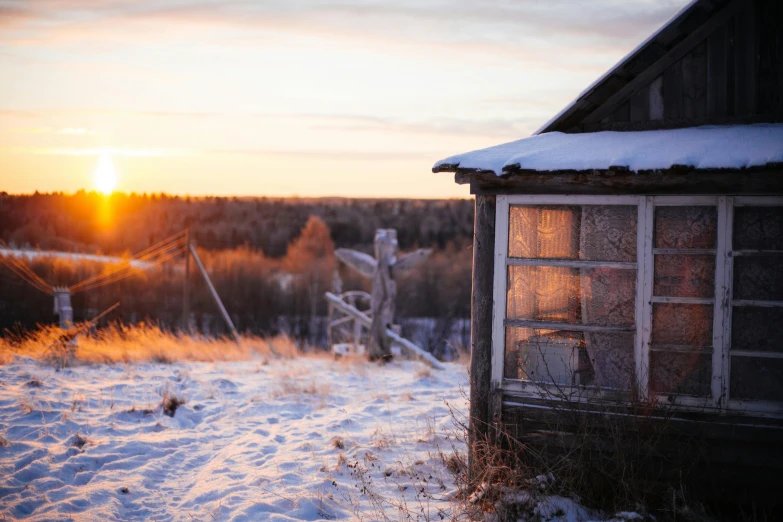 a cabin is sitting in the snow with the sun shining