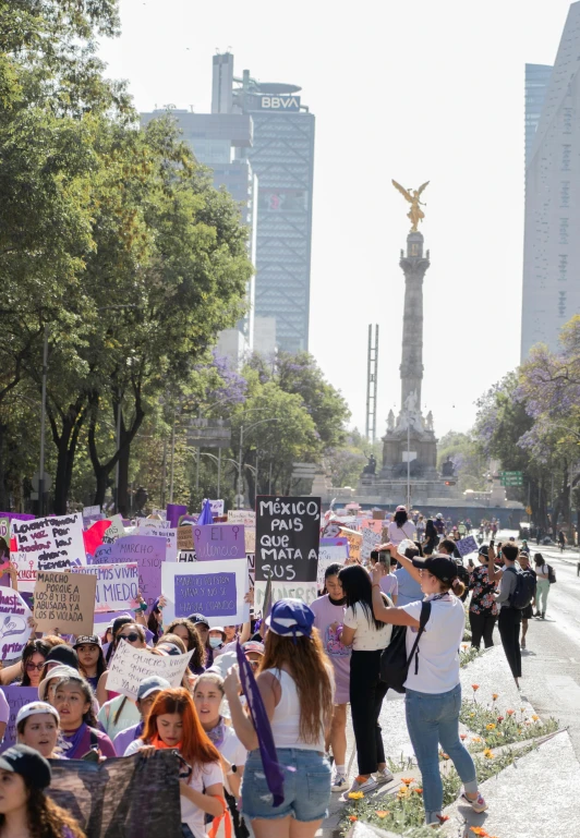 a large crowd of people holding signs and walking down the road