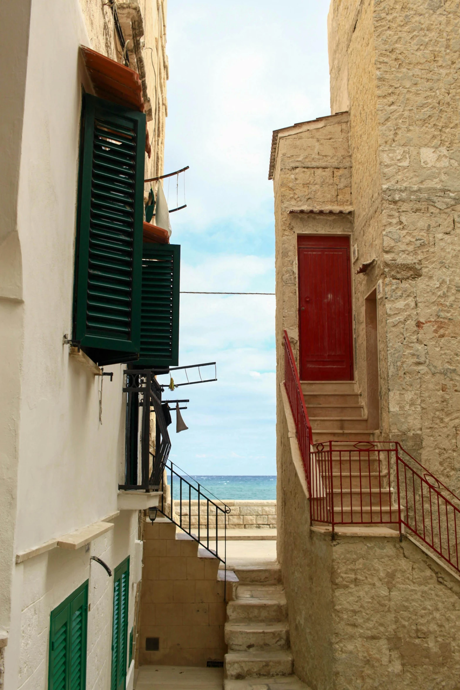 the entrance to a beach side alleyway with green shutters