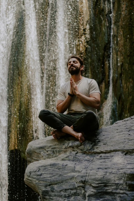 a man is sitting on a rock and praying