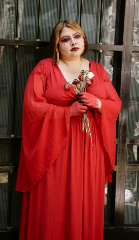 woman in red dress wearing fake makeup and holding flowers