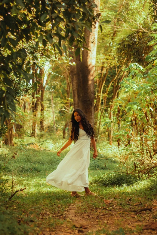 a girl in white is walking by a tree