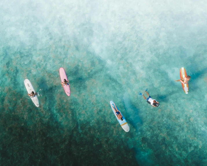 three people in small boats, one white, the other red, on blue and green water