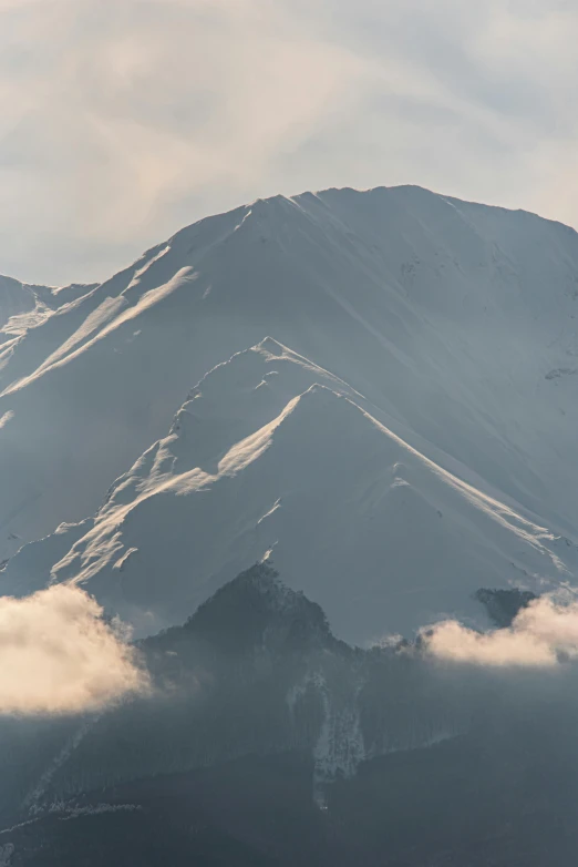 a mountain is covered in snow under a cloudy sky