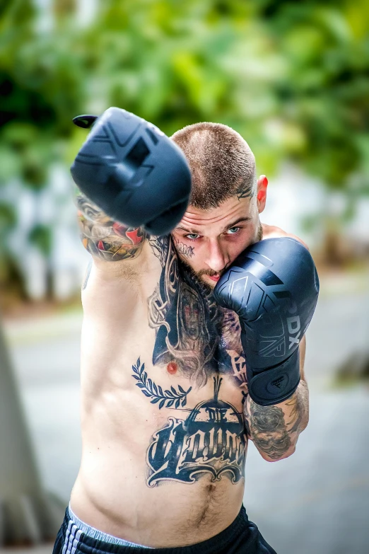 a man with some tattoos doing a kick with some boxing gloves