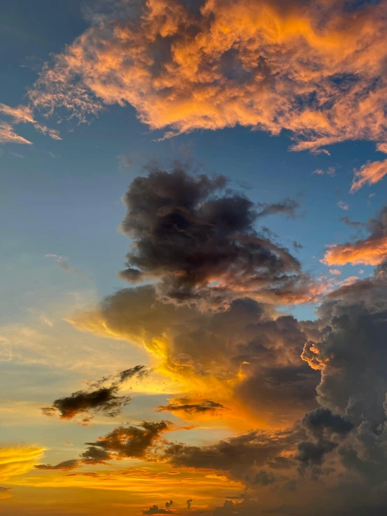 a sunset with clouds over the water and trees