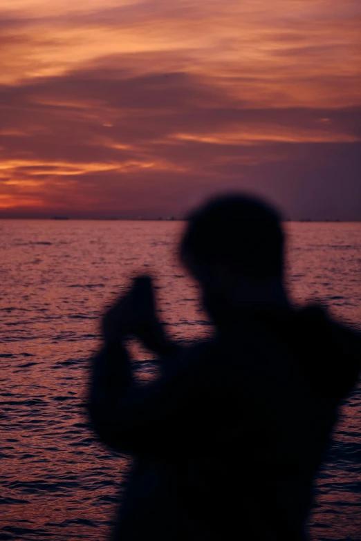 a man is taking a picture of the water with his cellphone