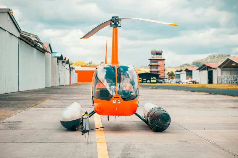 an orange helicopter is in the middle of an airport