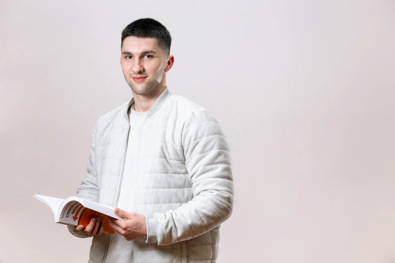 a man holding a book and smiling at the camera