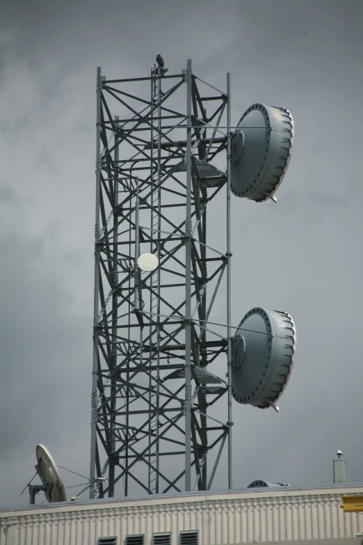 the top of a tall antenna tower has a plane flying by