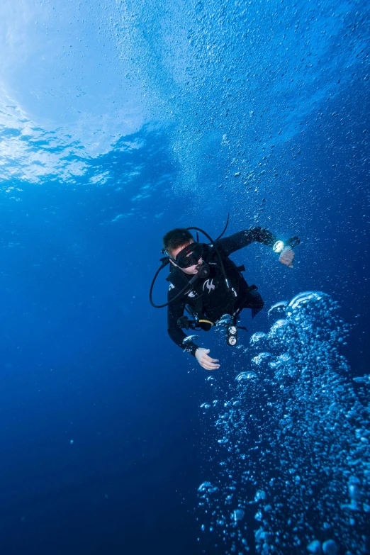 a man is swimming in the ocean, wearing a wetsuit and diving gear