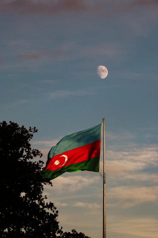 an flag and the moon in a cloudy sky