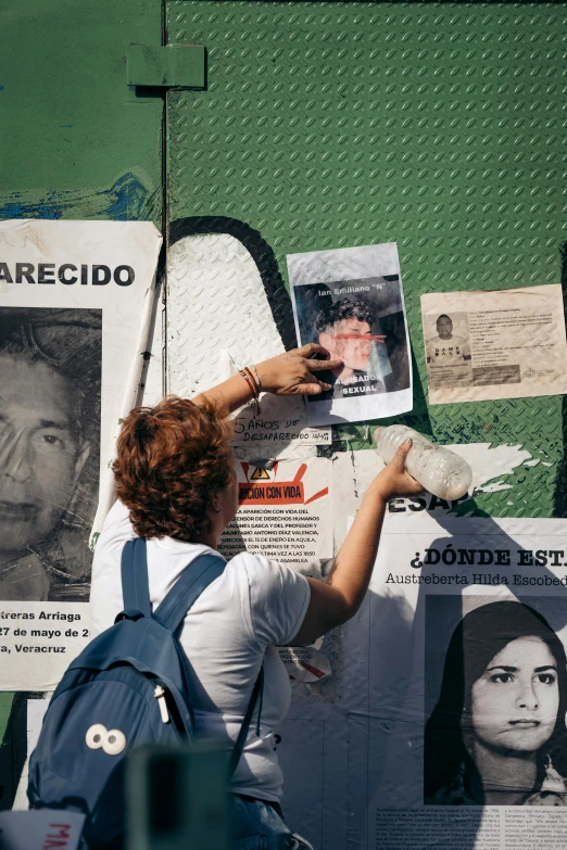 the young person is putting their hands up to put pictures on a wall