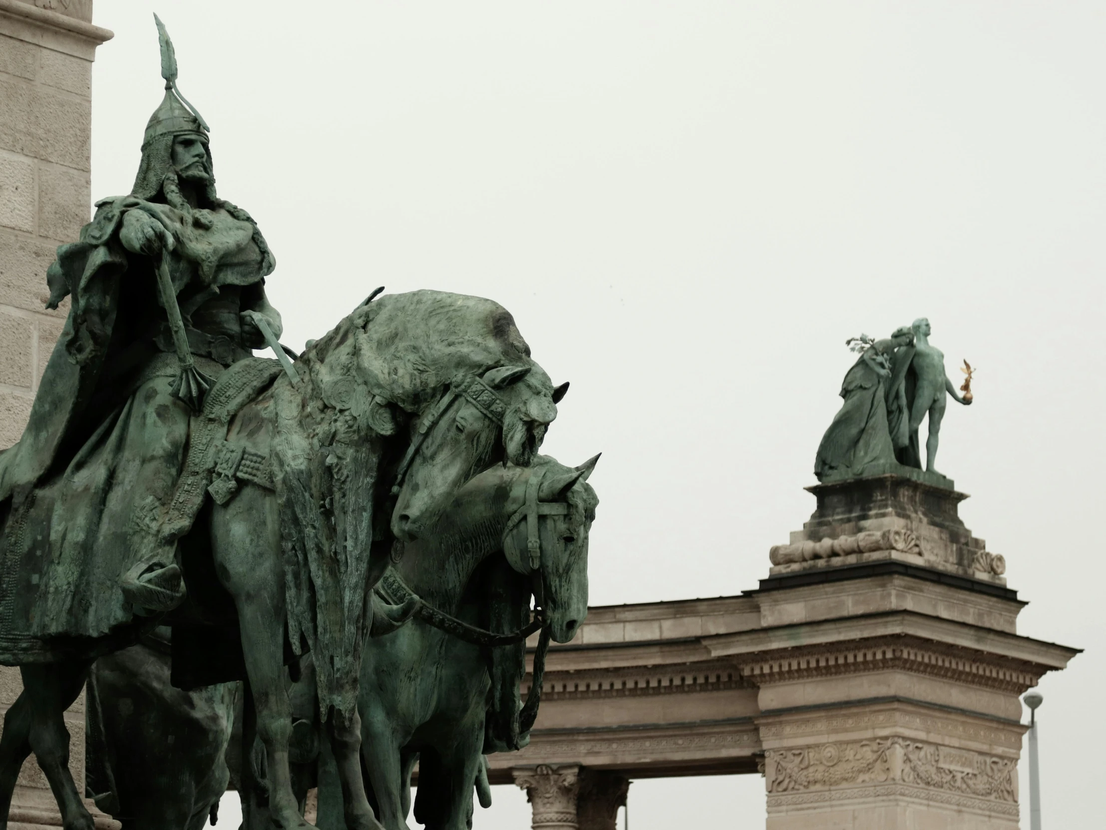 a close up of a bronze statue on a horse in front of an arch