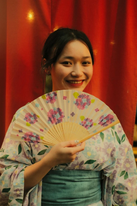 a woman wearing an oriental inspired dress holds a fan