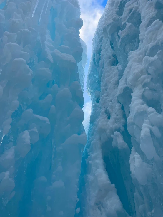 a lone skier moves through a very large ice wall