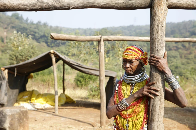 the two women in colorful clothes are hanging on wood poles