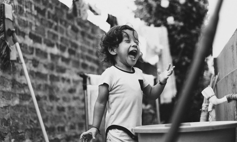 a child laughing while standing in front of a dumpster