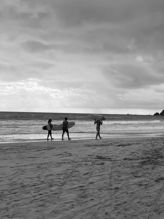 some people are standing on the beach holding surfboards