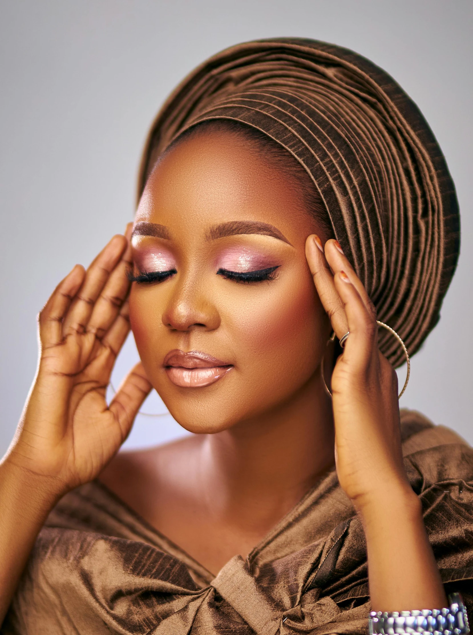 an african american woman with her hands on her temples, looking downward