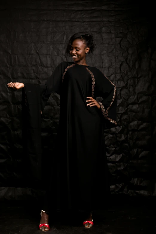 a woman is smiling while standing against a black backdrop