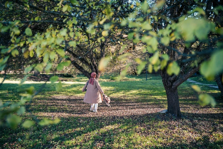 a woman walking in the shade in an apple orchard