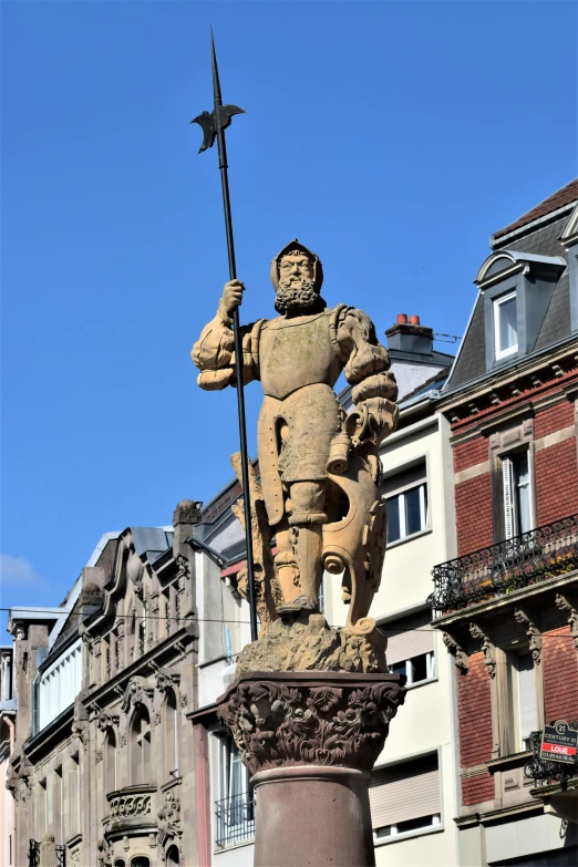 an statue with a pole on top stands in the middle of buildings