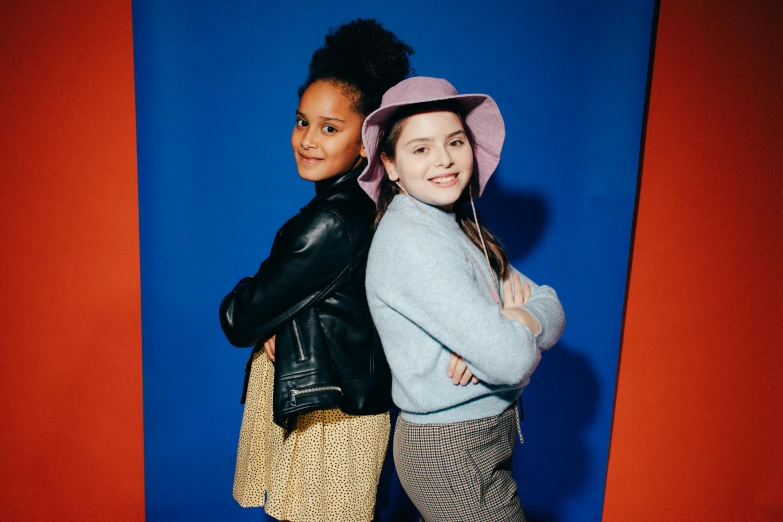 two young women hugging with a blue wall in the background