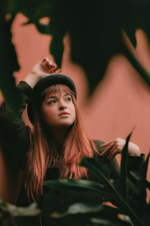 young woman leaning on a tree wearing a black hat