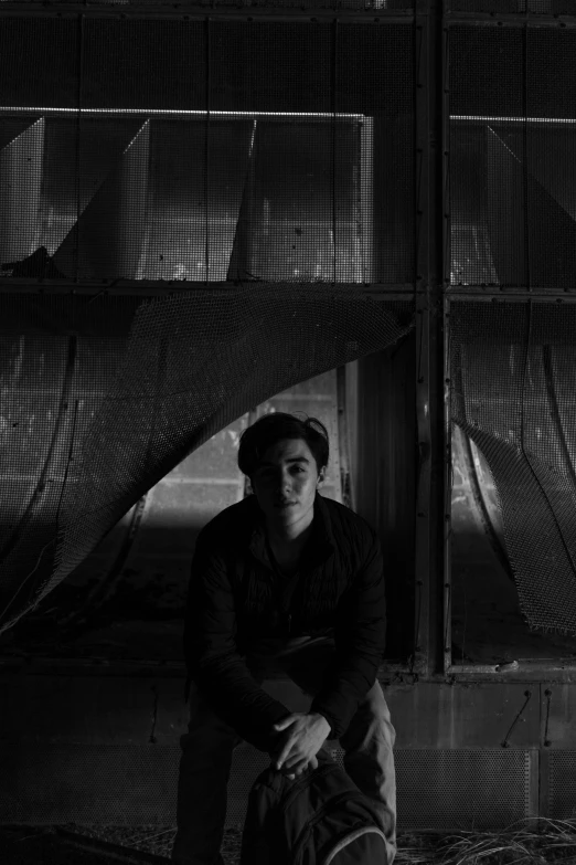 black and white po of young man sitting by a wall