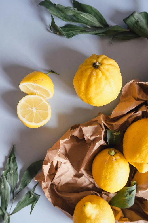 a table topped with yellow lemons and green leaves