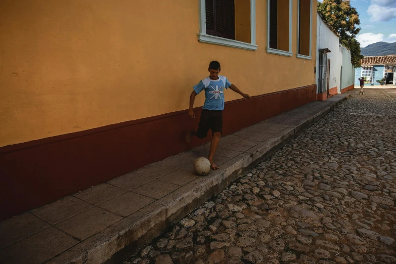 a person that is kicking a ball up the street