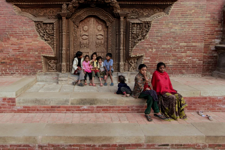 several children standing and sitting around on the steps