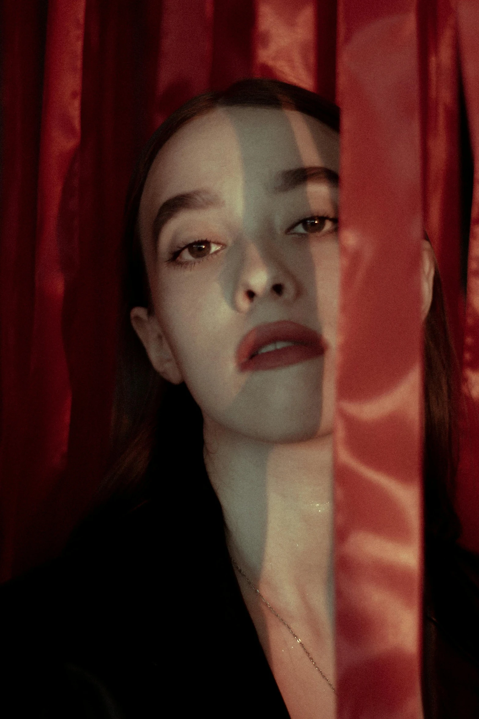 a close up of a woman standing in front of red curtains