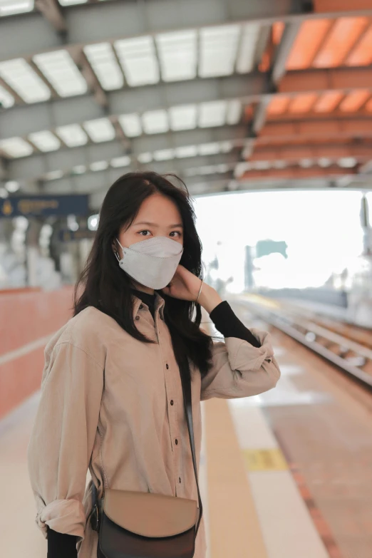 a woman wearing a mask walks along train tracks