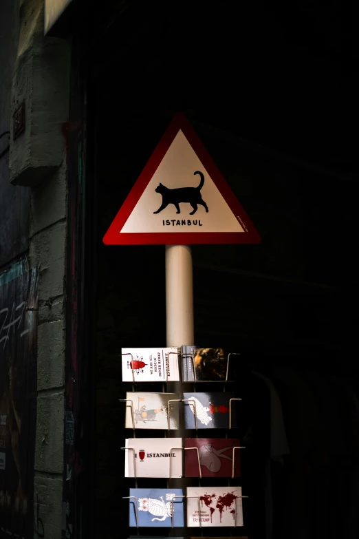 a pole with a warning sign that has a cat on it