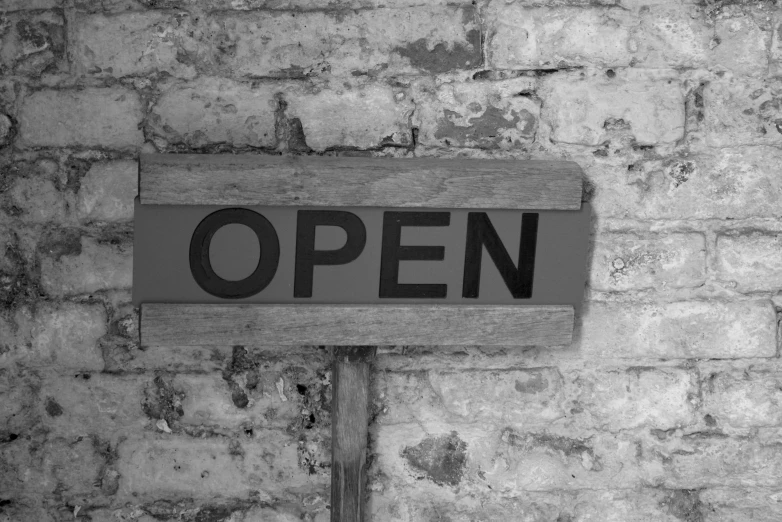 black and white pograph of a open sign on a brick wall
