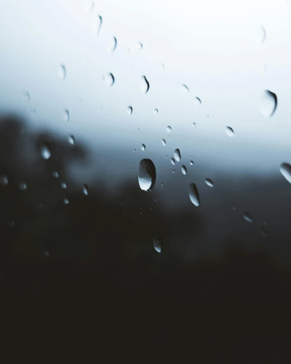 water drops on a window that are reflecting a blue sky