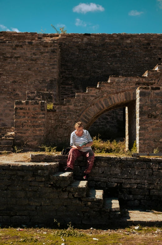 man sitting on stone staircase between two brick walls