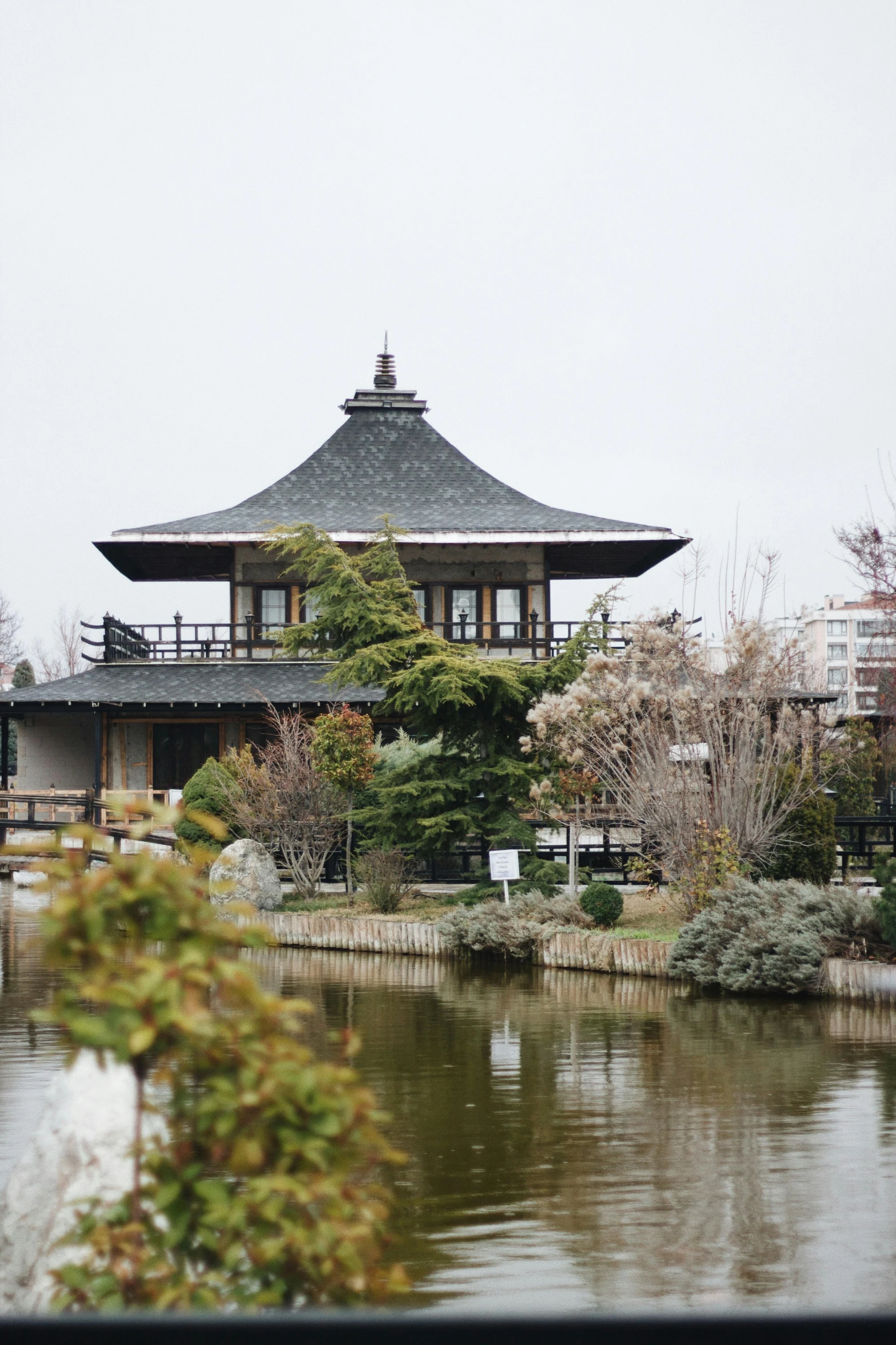 a building sitting by the water with trees