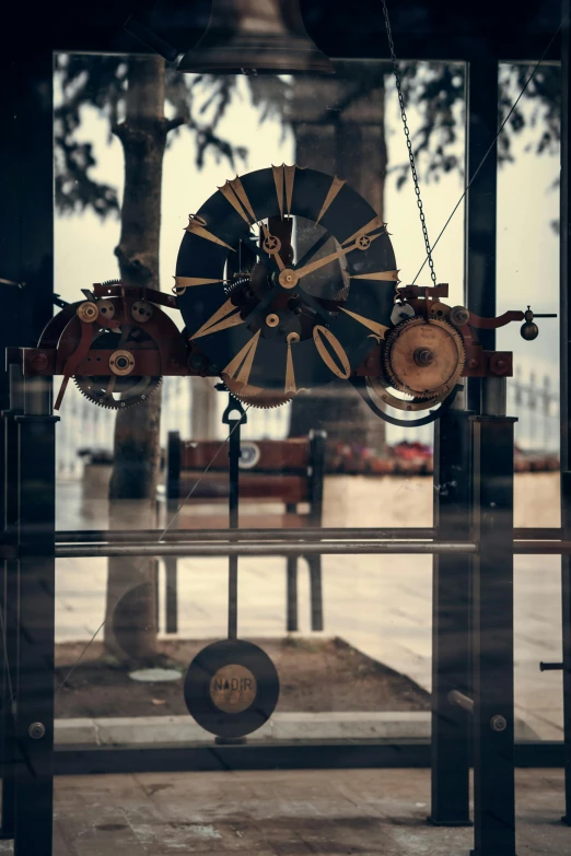 the reflection in a window shows clock face and bells